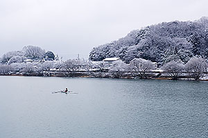 雪景色の瀬田川にボート乗りがひとり